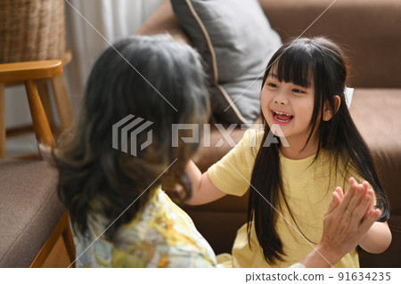 Joyful little grandchild playing with her grandmother, enjoying carefree leisure weekend activity together at home 91634235