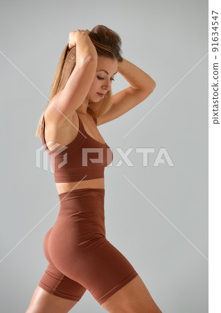 Young woman with beautiful slim healthy body posing in studio. Fitness female model in sportswear on grey background. 91634547