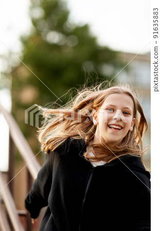 A teenage girl has fun and slides down the railing at the stadium A teenage girl has fun and slides down the railing at the stadium 91635883