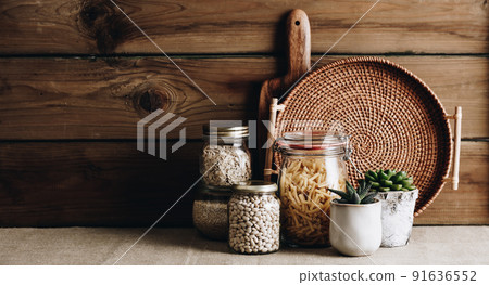 Eco-friendly kitchen concept: Kitchen cooking utensils, house plants and cooking ingredients in glass jars against rustic kitchen wall Eco-friendly kitchen concept: Kitchen cooking utensils, house plants and cooking ingredients in glass jars against rustic kitchen wall 91636552