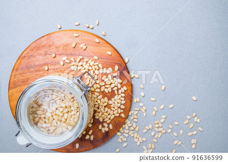 Flat lay. Glass jar with Siberian cedar nuts standing on a wooden stand.  91636599