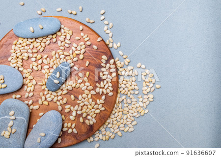 Oval gray stones on a wooden stand in a placer of Siberian cedar nuts. Oval gray stones on a wooden stand in a placer of Siberian cedar nuts. 91636607