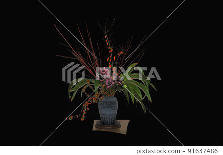 Red berries and green leaves and branches are arranged in a nice vase, creating a harmonious balance in this space. Red berries and green leaves and branches are arranged in a nice vase, creating a harmonious balance in this space. 91637486