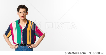 Image of confused and upset young man staring at camera, standing disappointed over white background Image of confused and upset young man staring at camera, standing disappointed over white background 91638032