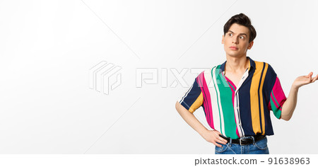 Confused gay man looking left at something strange, raising hand clueless and puzzled, standing over white background Confused gay man looking left at something strange, raising hand clueless and puzzled, standing over white background 91638963