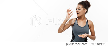 Healthy and Fitness concept - Closeup portrait of beautiful African American taking a pill of Cod liver oil. Isolated on white studio background. 91638993