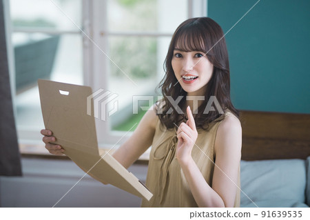 Lifestyle image of a young woman checking mail-order luggage in the room 91639535