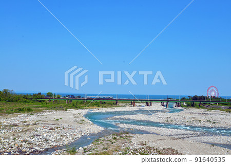[Uozu City, Toyama Prefecture] A train passing through the mouth of the Hayatsuki River 91640535