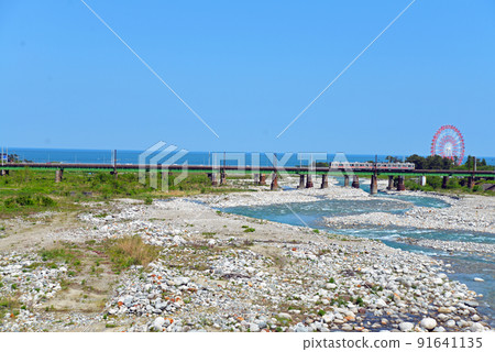 [Uozu City, Toyama Prefecture] A train passing through the mouth of the Hayatsuki River 91641135