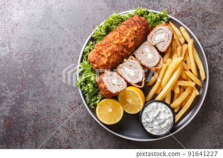 Karadjordjeva steak stuffed with kaymak, breaded and fried, served with french fries and tartar sauce close-up in a plate. horizontal top view Karadjordjeva steak stuffed with kaymak, breaded and fried, served with french fries and tartar sauce close-up in a plate. horizontal top view 91641227