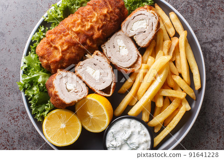 Karadjordjeva steak deep fried rolled veal or pork schnitzel served with fried potatoes with french fries and tartar sauce close-up in a plate. Horizontal top view Karadjordjeva steak deep fried rolled veal or pork schnitzel served with fried potatoes with french fries and tartar sauce close-up in a plate. Horizontal top view 91641228