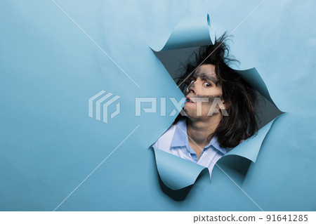 Insane chemist with amusing looks after failed laboratory experiment on blue background. Crazy mad scientist with funny face expressions, wacky hair and dirty face after chemical explosion. Insane chemist with amusing looks after failed laboratory experiment on blue background. Crazy mad scientist with funny face expressions, wacky hair and dirty face after chemical explosion. 91641285