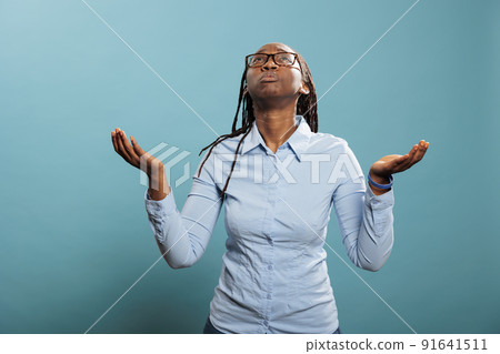 Faithful african american woman with palms faced to sky pleading and begging to have her sins forgiven. Religious and spiritual young person praying for a better and forgiving world. Studio shot Faithful african american woman with palms faced to sky pleading and begging to have her sins forgiven. Religious and spiritual young person praying for a better and forgiving world. Studio shot 91641511