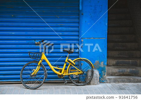 Yellow bicycle parked by the blue wall Yellow bicycle parked by the blue wall 91641756
