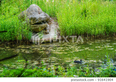 Dinosaur sculpture by the pond Dinosaur sculpture by the pond 91641904
