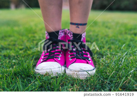 Girl in stylish pink sneakers standing on fresh green grass Girl in stylish pink sneakers standing on fresh green grass 91641919