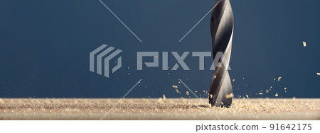 Metal wet drill bit make holes in wooden surface on industrial drilling machine with shavings on gray background. Photo with copy space. 91642175