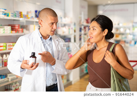 Woman complaining about toothache to pharmacist 91644024