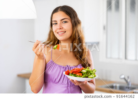 Portrait of girl eating salad at home Portrait of girl eating salad at home 91644162