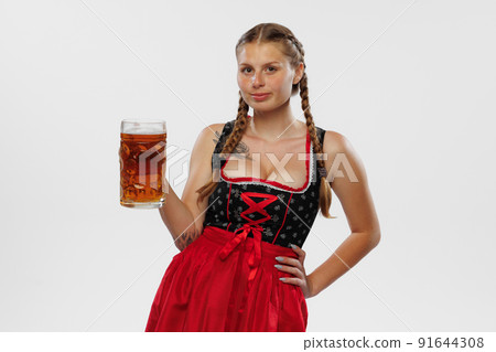 Adorable smiling woman, waitress wearing a traditional Bavarian or german dirndl holding big mug of beer isolated on white background. Holiday, event, oktoberfest, 91644308