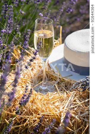 A glass of champagne and straw hat on a bale of hay 91644364