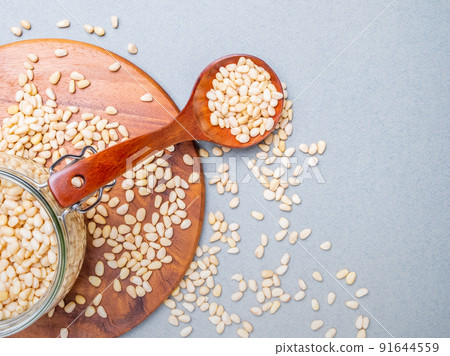 Flat lay. Glass jar with Siberian cedar nuts standing on a wooden stand.  91644559