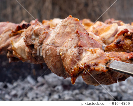 Juicy slices of pork meat are strung on skewers and grilled in charcoal grill. Juicy slices of pork meat are strung on skewers and grilled in charcoal grill. 91644569