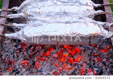The meat on metal skewers is wrapped in aluminum foil and grilled on charcoal. The meat on metal skewers is wrapped in aluminum foil and grilled on charcoal. 91644572