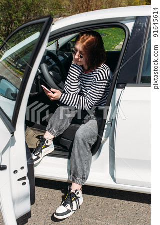 Portrait of a young brunette woman driving in a car using a smartphone Portrait of a young brunette woman driving in a car using a smartphone 91645614
