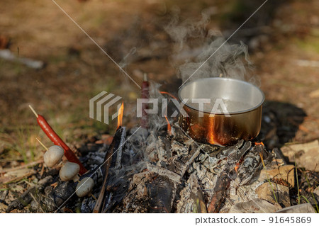 Cooking food in pot on campfire..The concept of adventure, travel, tourism, camping, survival and evacuation. 91645869