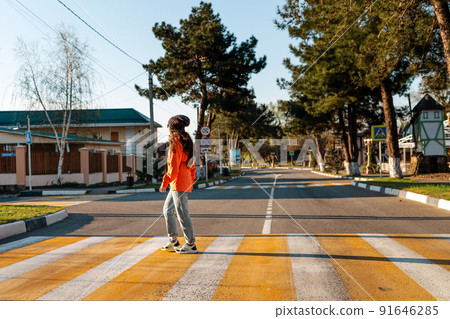 A young woman crosses a pedestrian crossing. Empty road and streets. Sunny. Concept of traffic rules 91646285
