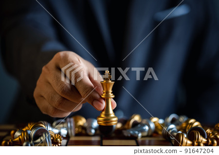 closeup hand of businessman holding chess piece in competition play 91647204