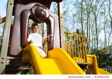 Active blonde little girl playing on a playground Active blonde little girl playing on a playground 91648340