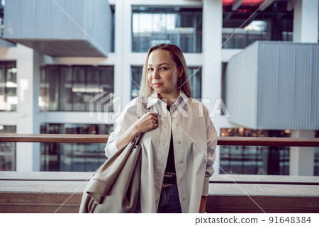 Portrait of young office woman standing on balcony enjoying city view 91648384