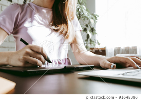 Close up of female graphic designer drawing sketches on graphic tablet 91648386