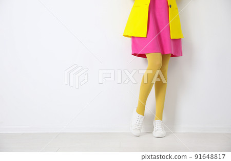 Woman wearing yellow tights near white wall, closeup. Space for text 91648817