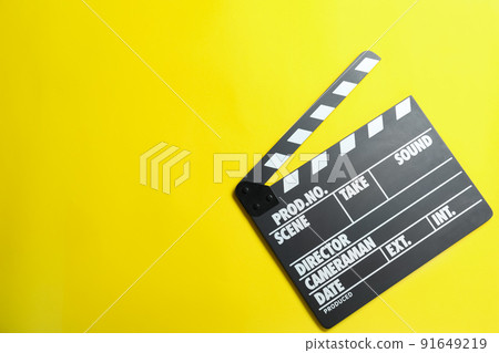 Clapper board on yellow background, top view with space for text. Cinema production 91649219