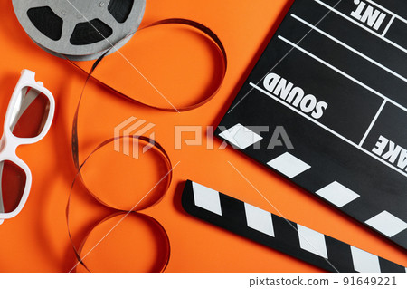 Flat lay composition with clapperboard on orange background. Cinema production 91649221