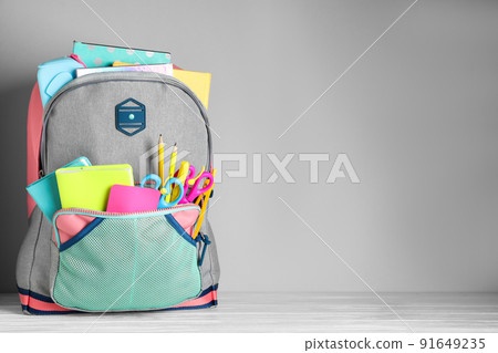 Stylish backpack with different school stationery on table against light grey background 91649235