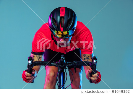 Closeup portrait of professional cyclist in red sports uniform, goggles and helmet on a blue background. Concept of active life, rest, travel, energy, sport Closeup portrait of professional cyclist in red sports uniform, goggles and helmet on a blue background. Concept of active life, rest, travel, energy, sport 91649392