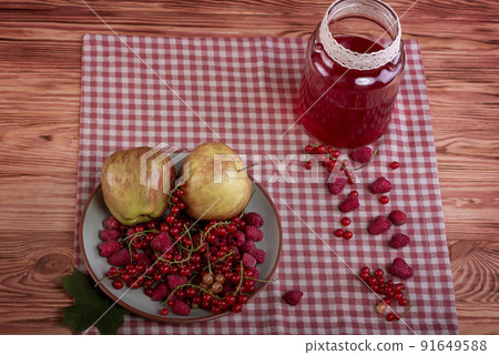 Compote, red currants, raspberries and apples on an old wooden table. 91649588
