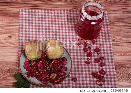 Compote, red currants, raspberries and apples on an old wooden table. 91649596