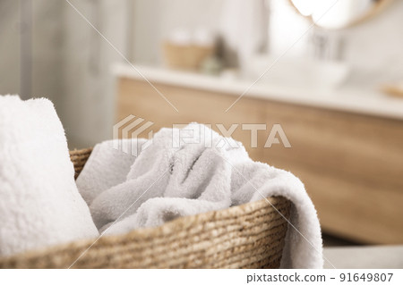 Wicker basket with clean towels in bathroom, closeup 91649807