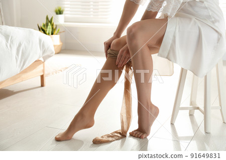 Young woman putting on tights in bedroom, closeup 91649831