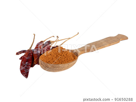 Wooden spoon full of ground red pepper and pepper pods on a white background. 91650288