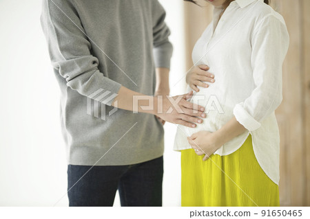A couple talking with a hand in the tummy of a pregnant woman 91650465