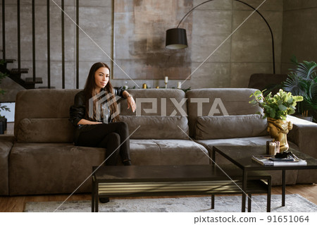 portrait of a beautiful young woman sitting on a sofa portrait of a beautiful young woman sitting on a sofa 91651064