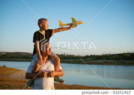 Dad and son in nature with an airplane Dad and son in nature with an airplane 91651407