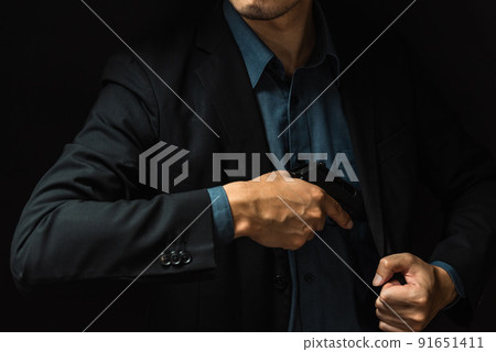 A person in a suit holding a pistol 91651411
