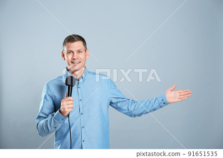 Male journalist with microphone on grey background Male journalist with microphone on grey background 91651535